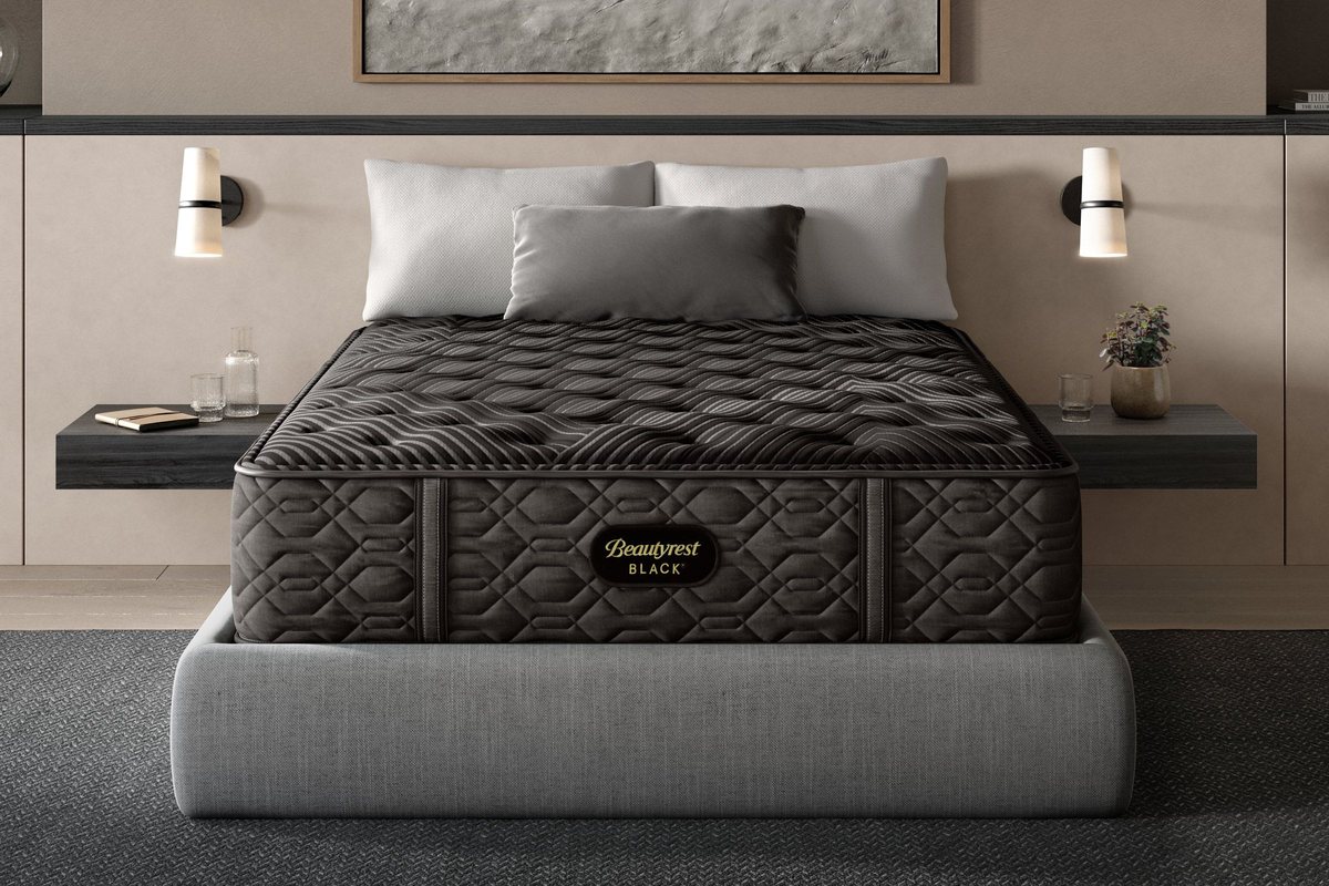A Beautyrest Black mattress in a warm, low-lit bedroom