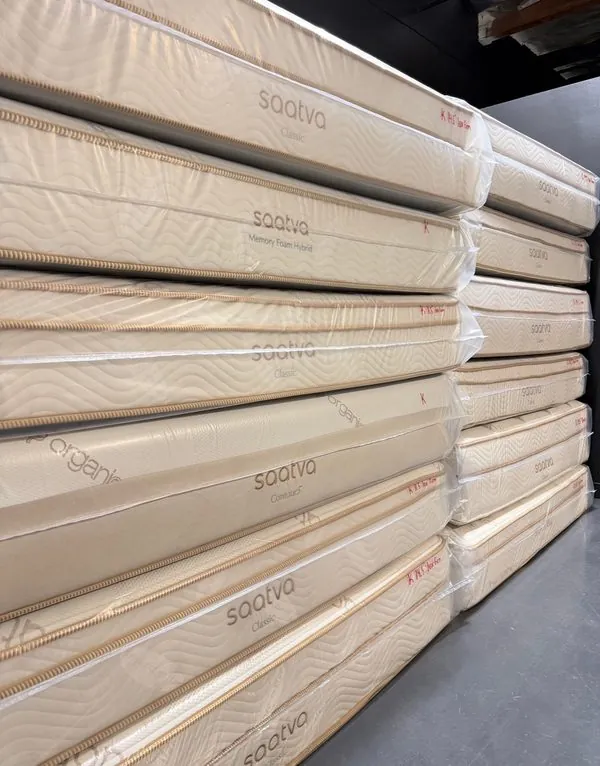 A long row of stacked Saatva mattresses running down the warehouse floor