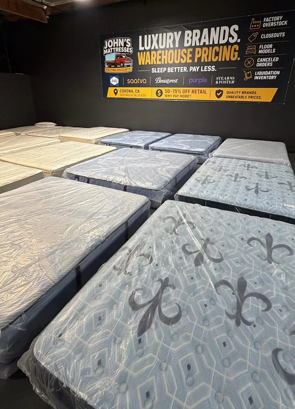 The showroom area under the John's Mattresses banner reading Luxury Brands, Warehouse Pricing, Sleep Better, Pay Less