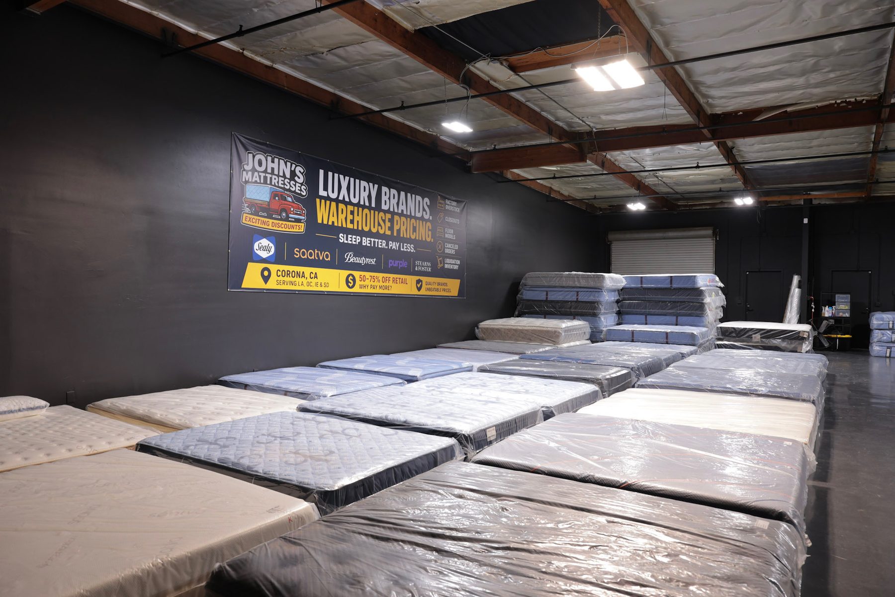 Filas de colchones envueltos en la bodega con inventario apilado detrás